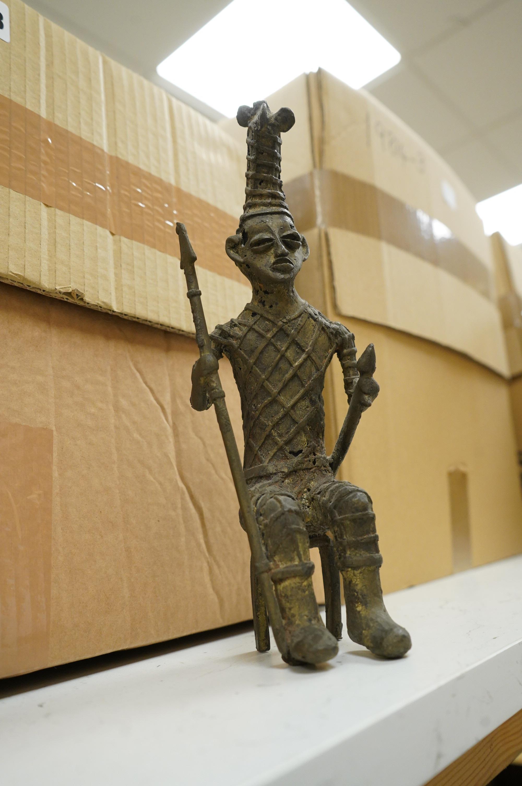 Five ethnographic items; an early 20th century chip carved Australian boomerang-60cm long , together with a later example, a Benin bonds of a warrior seated on a stool, a Makonde African carved figure group and an Africa